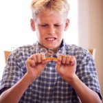 boy breaking pencil from bin